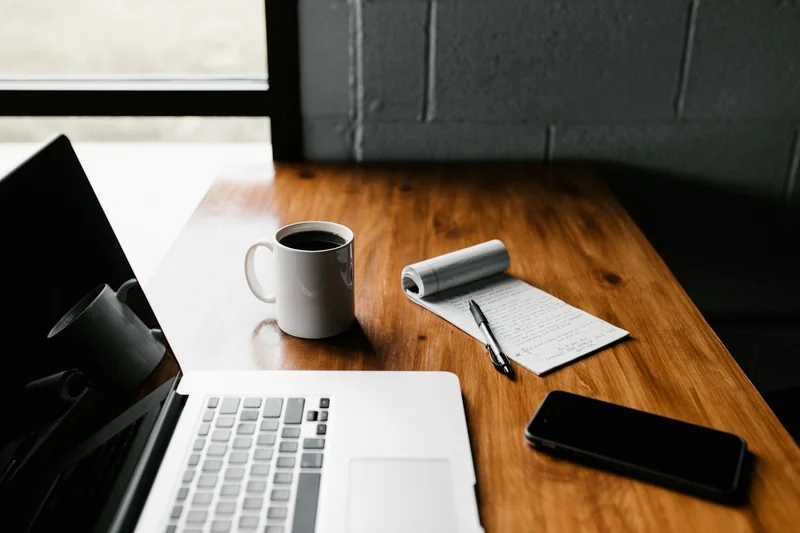 Bureau d'un indépendant avec carnet, ordinateur portable et tasse de café