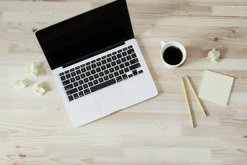 Plan de travail en bois clair avec ordinateur portable et bloc-notes